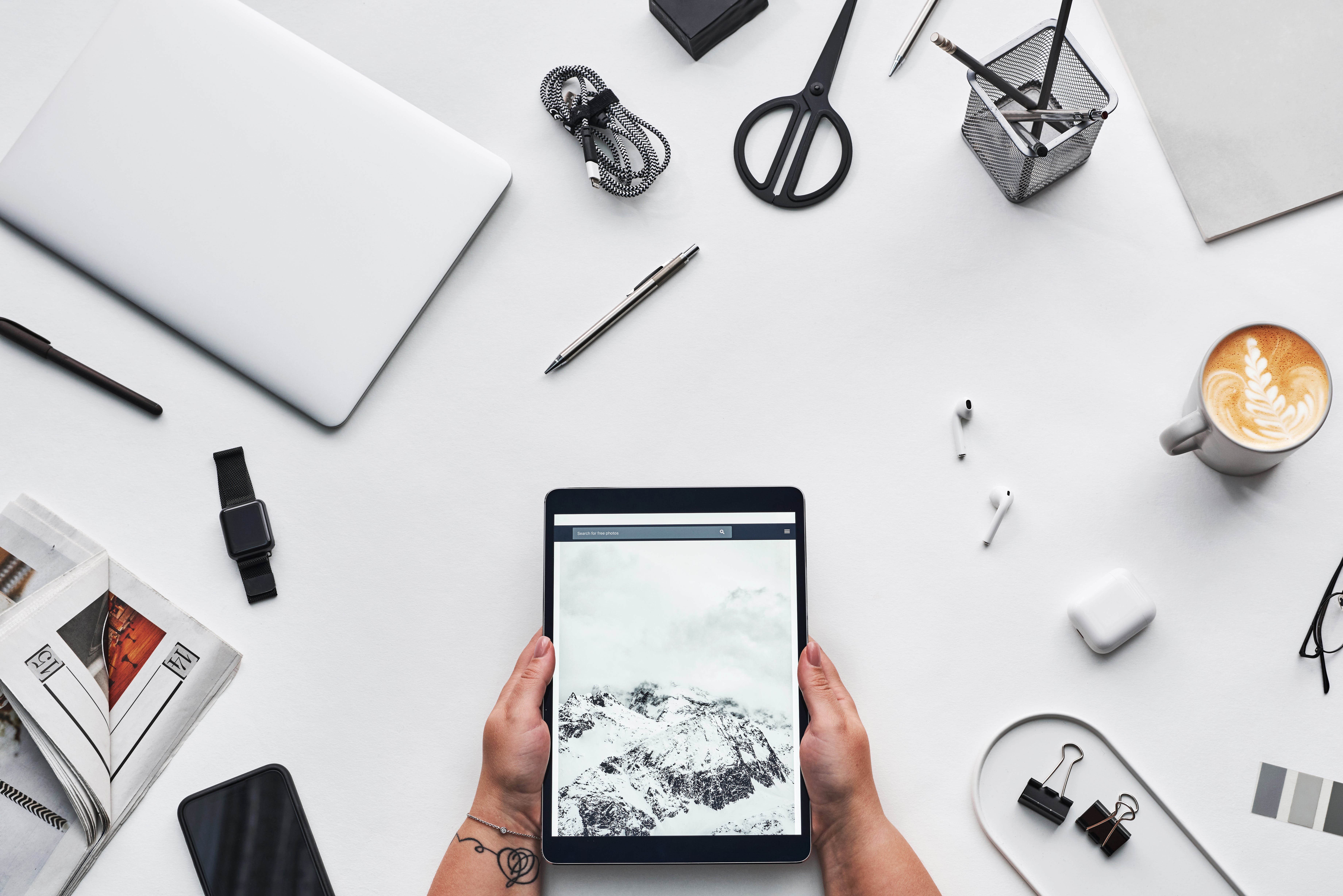 desk full of writing utensils and 
    a pair of hands holding a tablet